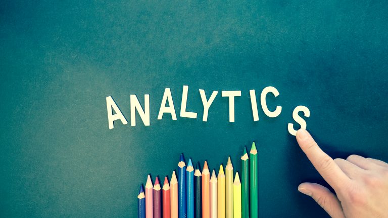 words on a green blackboard spells out "analytics" with color pencils.