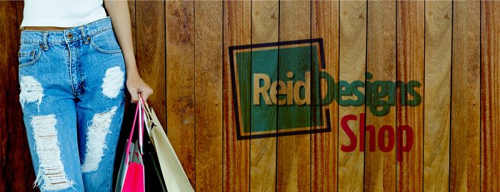 A woman with torn jeans holing shopping bags against a wooden wall. "Reiddesigns Shop"