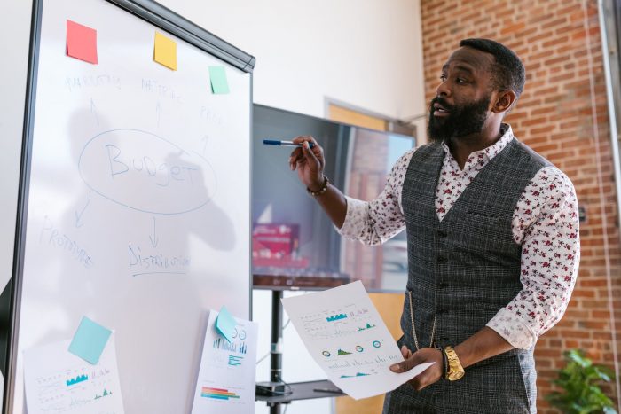man in gray and black blazer holding white printer paper. UX Agency goals